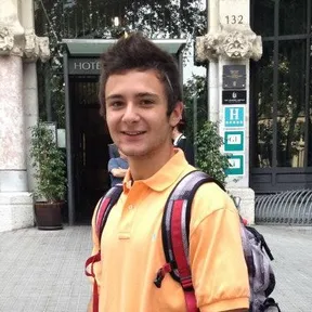 Kevin on a Barcelona street outside a hotel doorway, a backpack strap over one shoulder, turning to grin at the camera.